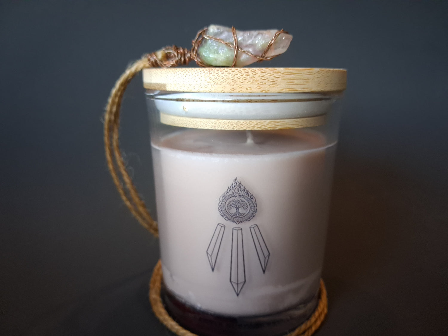 The Knowing candle with bamboo lid topped with wire-wrapped amethyst crystal pendant on jute cord, cream wax with Awen Aboros logo