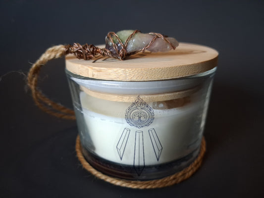 Citrine Intentions candle with bamboo lid topped with wire-wrapped crystal pendant on jute cord, cream wax with Awen Aboros logo, dark background