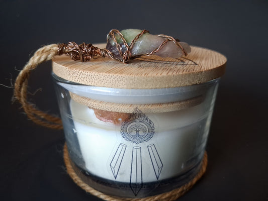 Champagne Aura Intentions candle with bamboo lid topped with wire-wrapped multi-stone crystal pendant on jute cord, cream wax with Awen Aboros logo, dark background